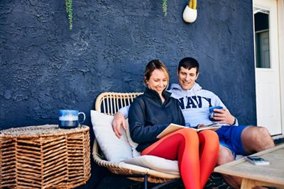 Navy man and wife sitting outside reading while having coffee