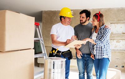 Happy contractor talking to a couple while remodeling their house - home improvement concepts