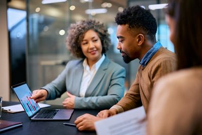 African American man and insurance agent looking at his financial reports on laptop during a meeting in the office.