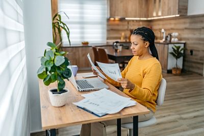 Young black woman checking her finances on a laptop at home at night.