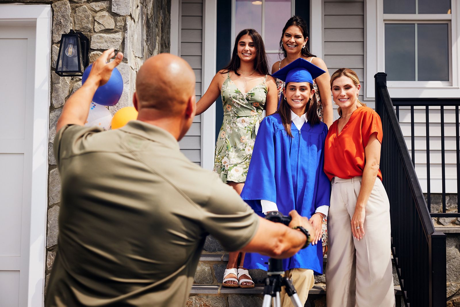 Dad taking a photo of school graduate with mother and friends