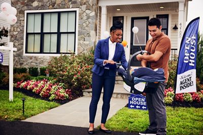 Wide angle of Realtor greeting new client with baby to open house 