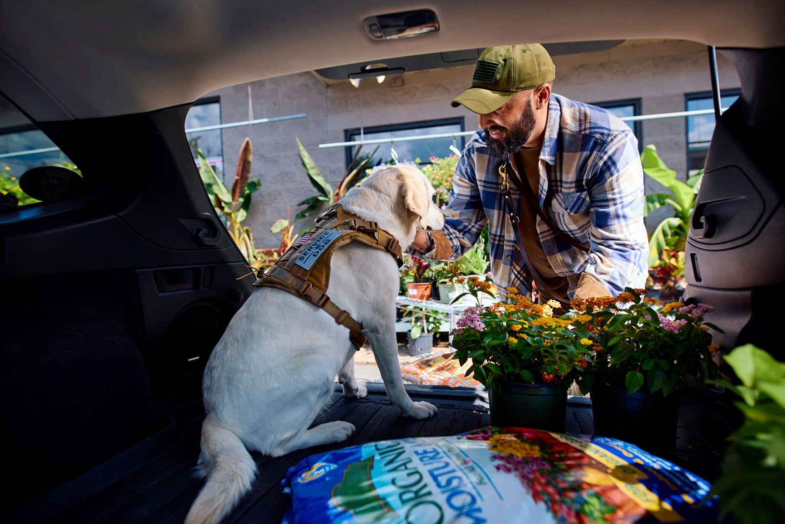 Man with dog loading plants in car