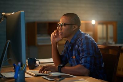 Handsome African American financial manager preparing annual accounts while working overtime in modern open plan office