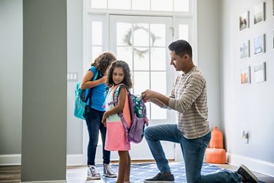 Father packing daughters backpacks for school