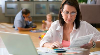 Woman working from home while father and child play in background