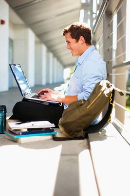 college student smiling at laptop 