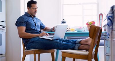 Man on laptop while having breakfast in kitchen