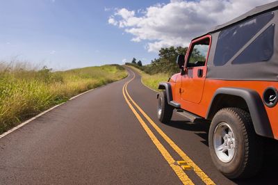 Jeep driving down open road.