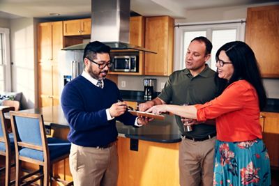 Couple checking on list of must have items with real estate agent.