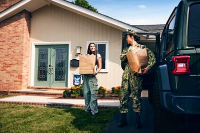 Military mom and daughter unloading jeep of groceries