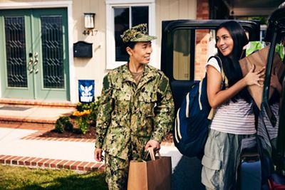 Military mom and daughter unloading jeep of groceries