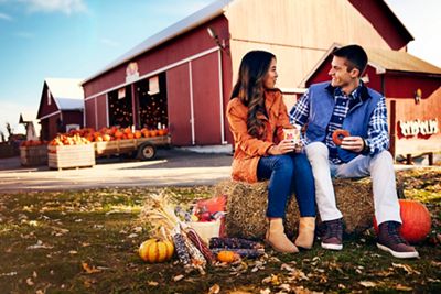 Wide shot of young couple enjoying a snack while on a pumpkin patch date