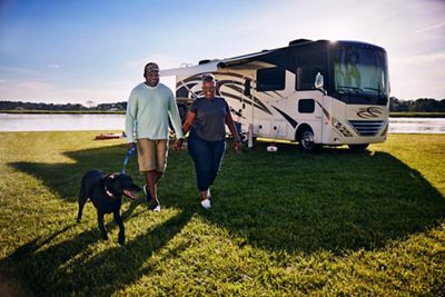 Couple taking their dog for a walk while on a camping trip